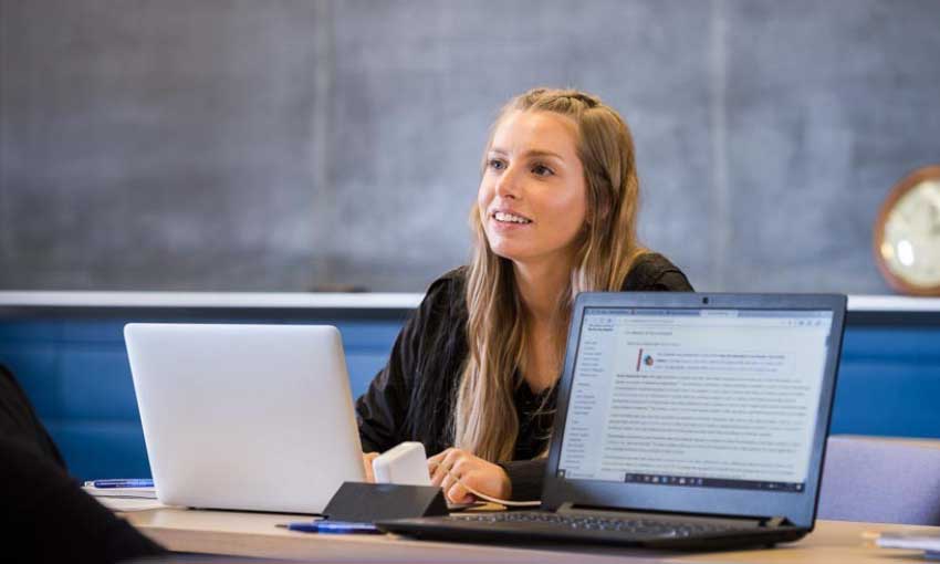 A female student works on a laptop in a classroom